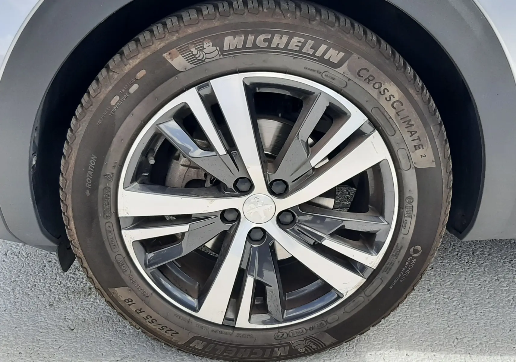 Gros plan sur la jante alliage bicolore et pneu Michelin CrossClimate 2 du côté avant droit d'un Peugeot 3008 gris.