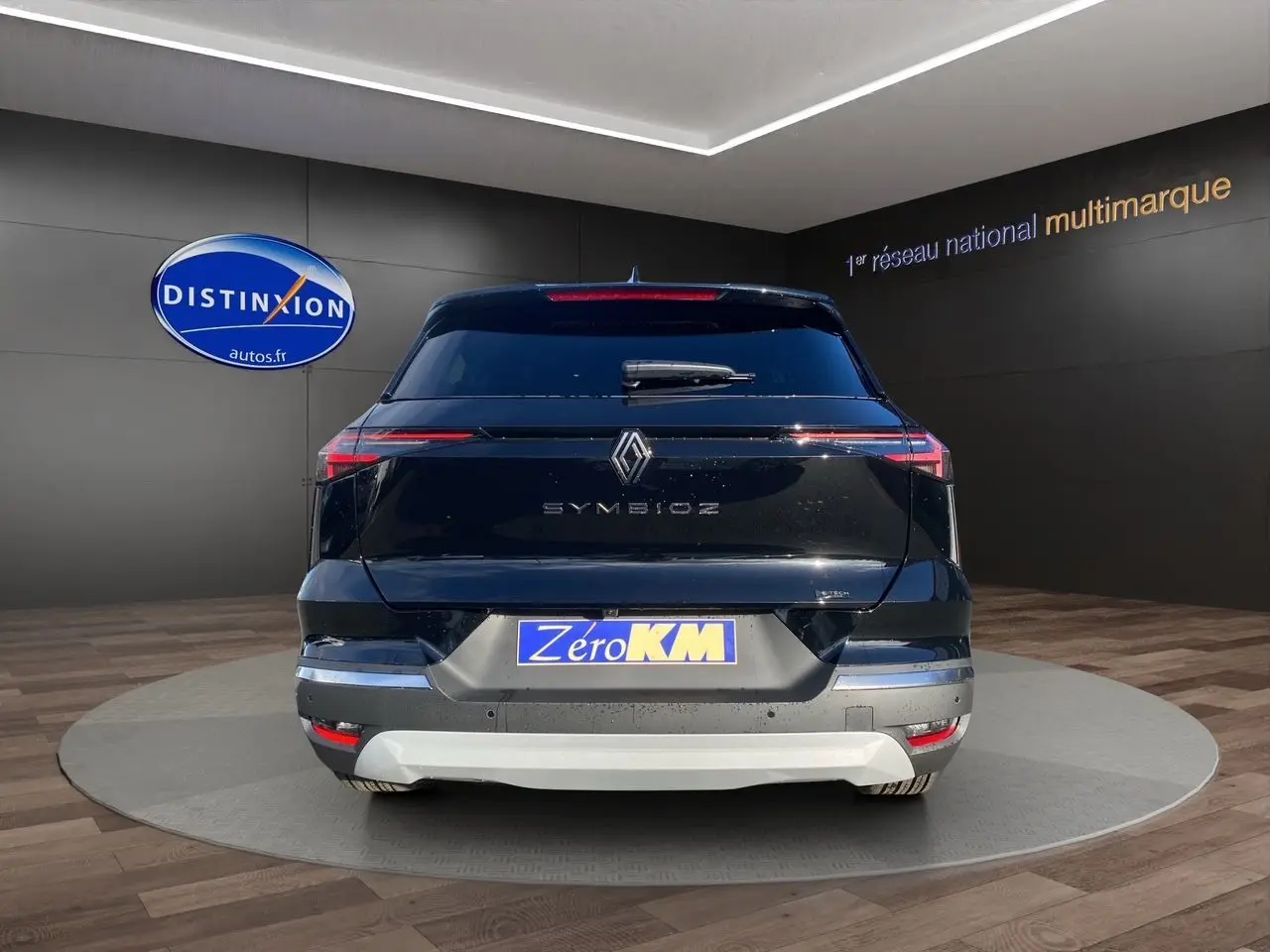 Vue arrière d'une Renault Symbioz noire étoile avec feux LED fins et plaque Zéro KM dans un showroom.