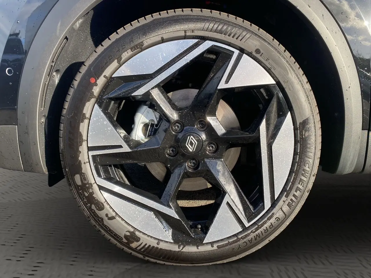 Gros plan sur la jante alliage bicolore noire et argentée du Renault Symbioz noir étoile, avec logo central Renault.