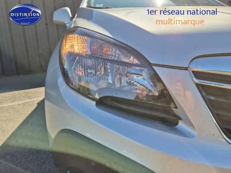 Gros plan sur le phare avant droit d'un Opel Mokka gris Astéroïde avec calandre chromée visible