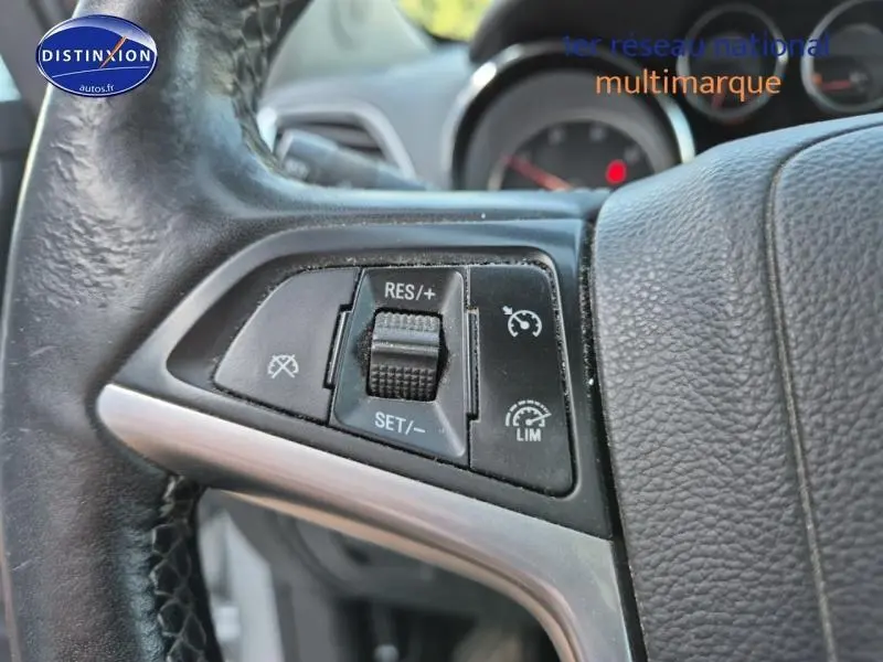 Gros plan sur les commandes de régulateur de vitesse au volant cuir noir de l'Opel Mokka gris Astéroïde 2016.