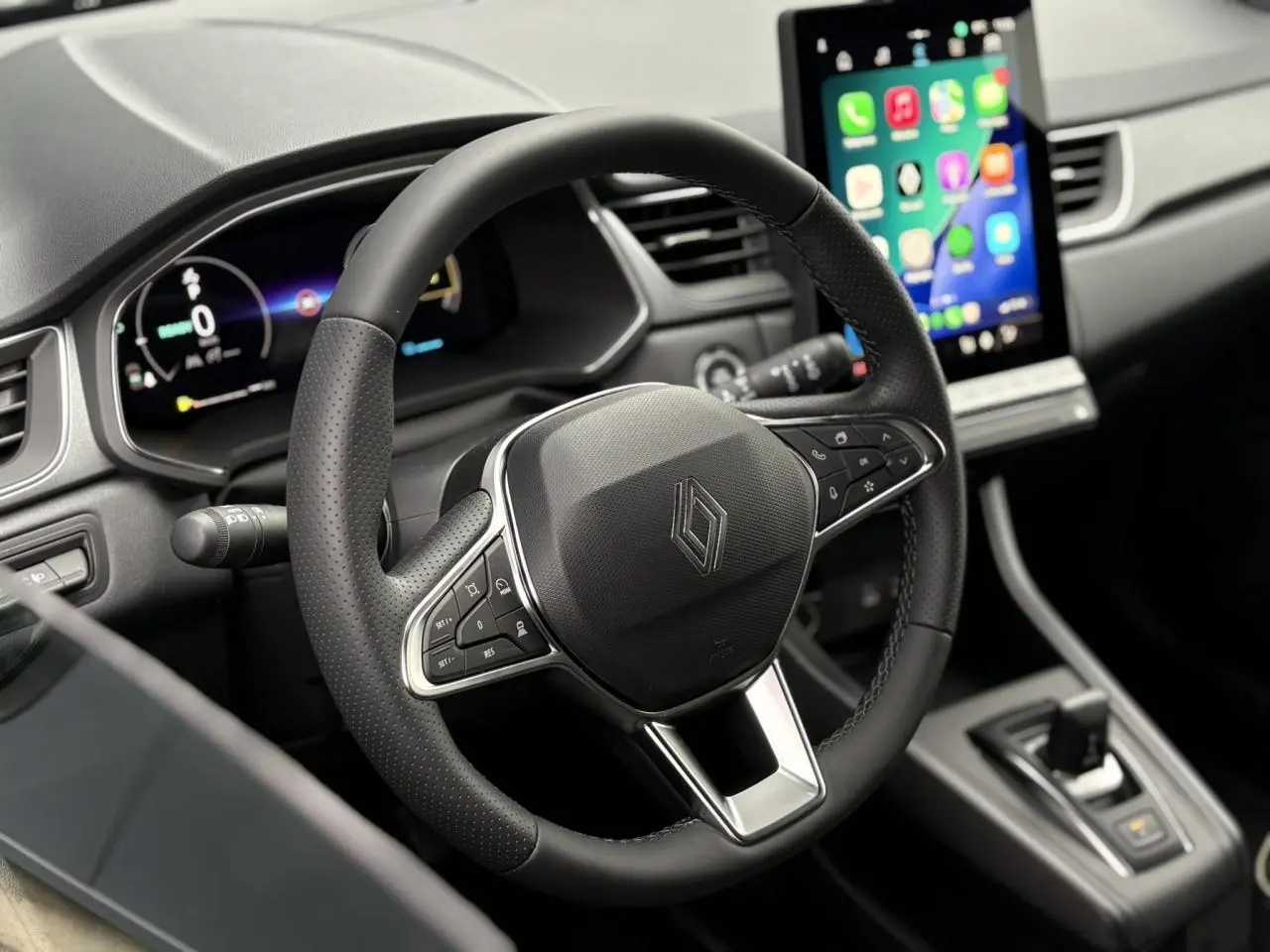 Vue rapprochée du volant noir et du tableau de bord numérique du Renault Captur 2025 avec écran tactile central allumé.