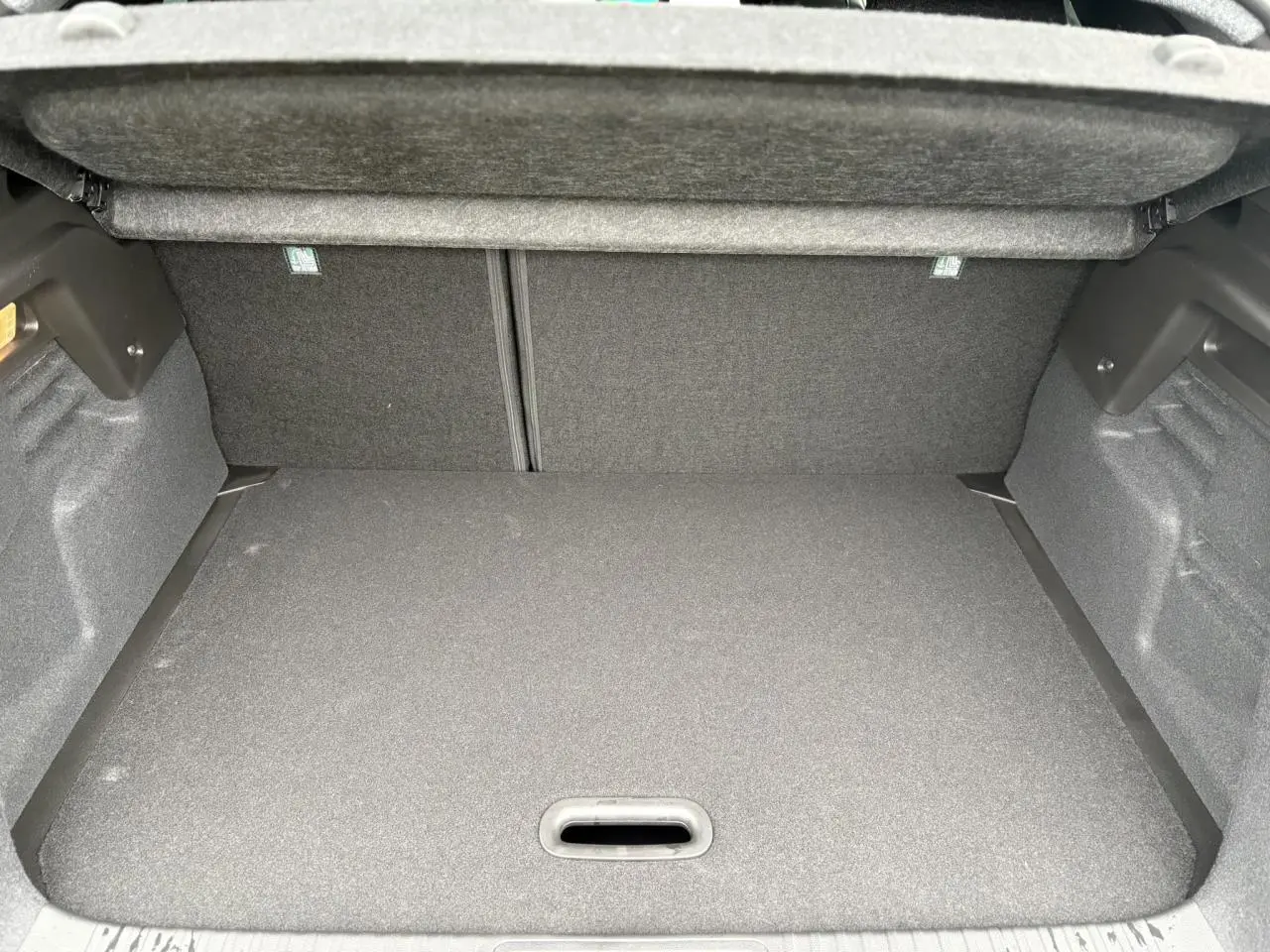 Vue intérieure du coffre spacieux et couvert du Renault Captur 2025, version hybride, avec revêtement gris foncé.