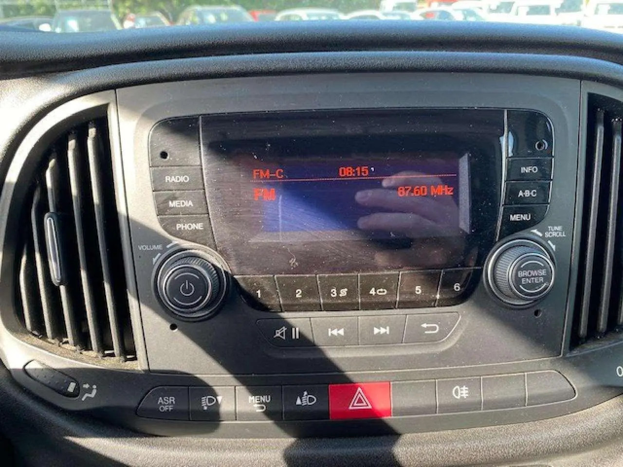 Vue rapprochée du tableau de bord du Fiat Doblo blanc 2017, mettant en valeur l’autoradio et les commandes centrales.