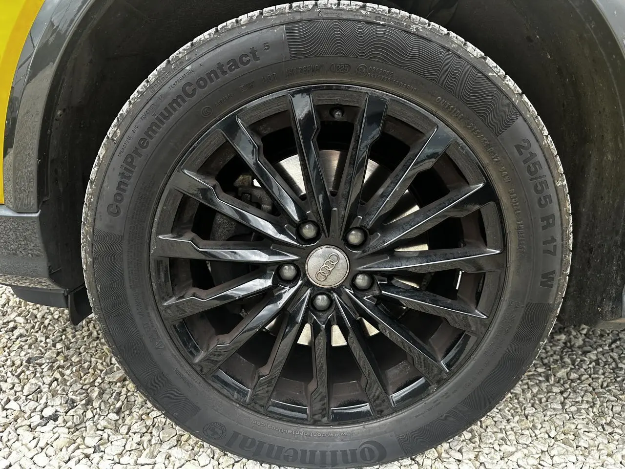 Gros plan sur la jante en aluminium noire multi-branches de l'Audi Q2 jaune, avec pneu Continental 215/55 R17 visible.
