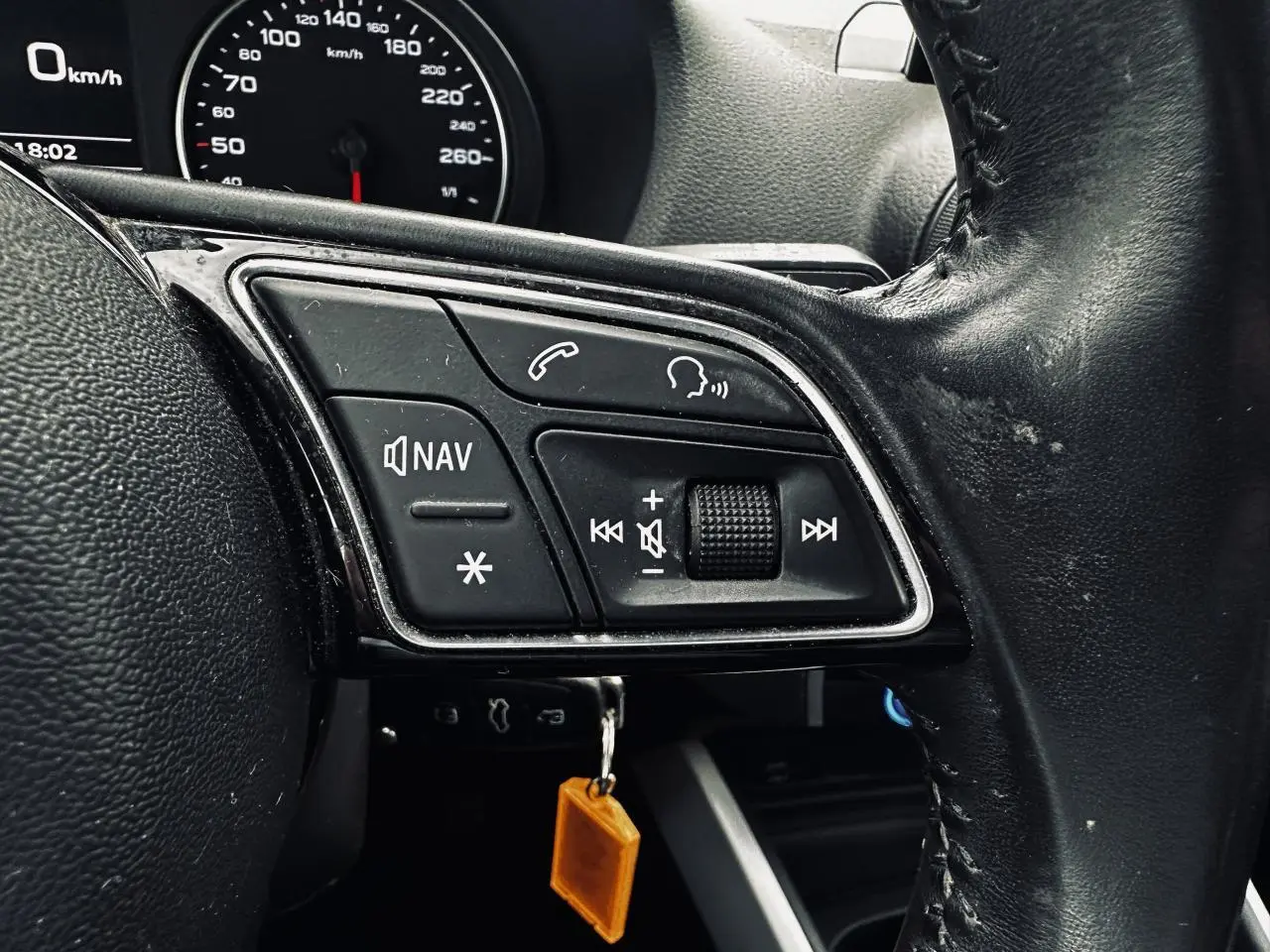 Gros plan sur les commandes gauche du volant en cuir noir de l'Audi Q2 1.6 TDI Business line, avec tableau de bord partiel visible.