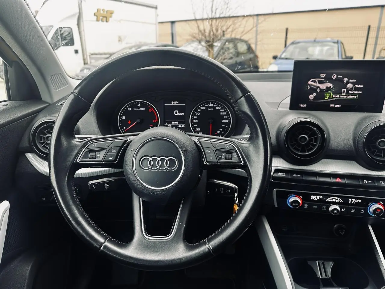 Vue intérieure centrée sur le volant multifonction noir de l'Audi Q2 1.6 TDI 2017 avec tableau de bord et écran multimédia.