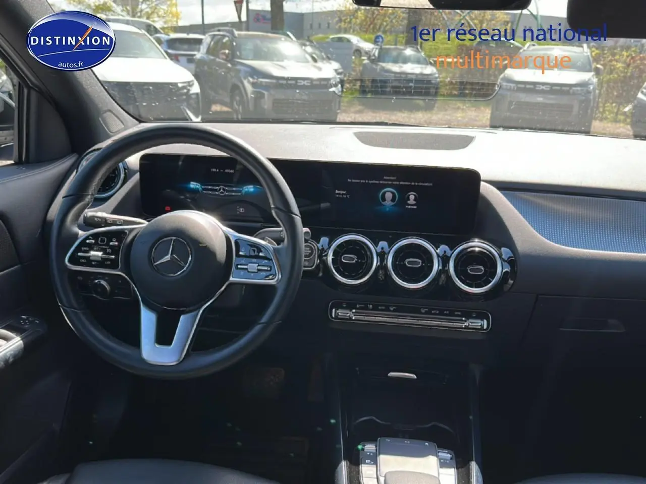 Vue intérieure avant du tableau de bord noir du Mercedes GLA 200 2022 avec volant cuir multifonction et écran tactile large.