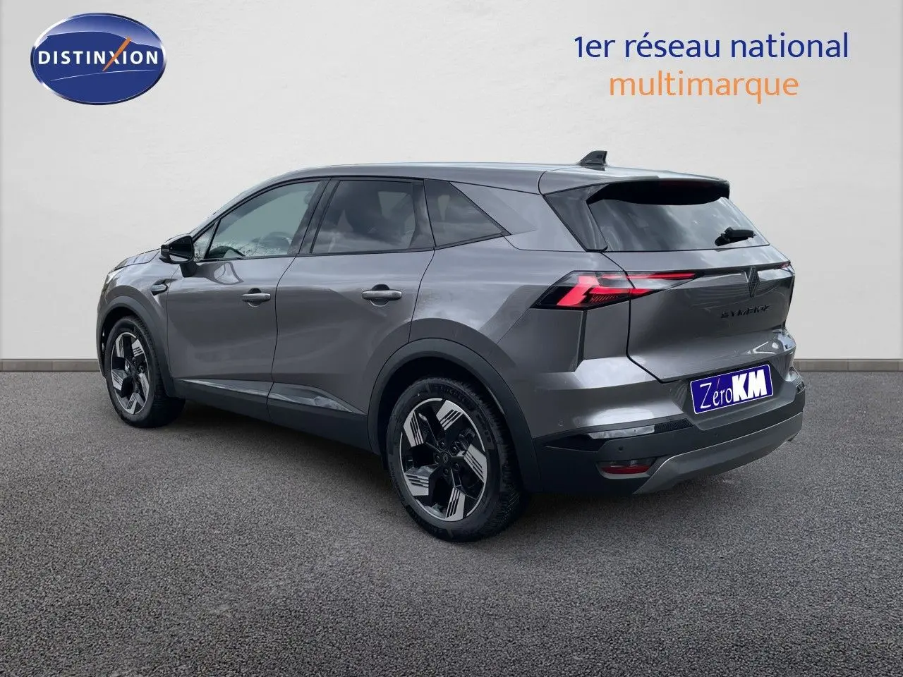 Renault Symbioz gris cassiopée métal en 3/4 arrière droit, SUV hybride avec feux arrière LED fins et jantes bicolores.