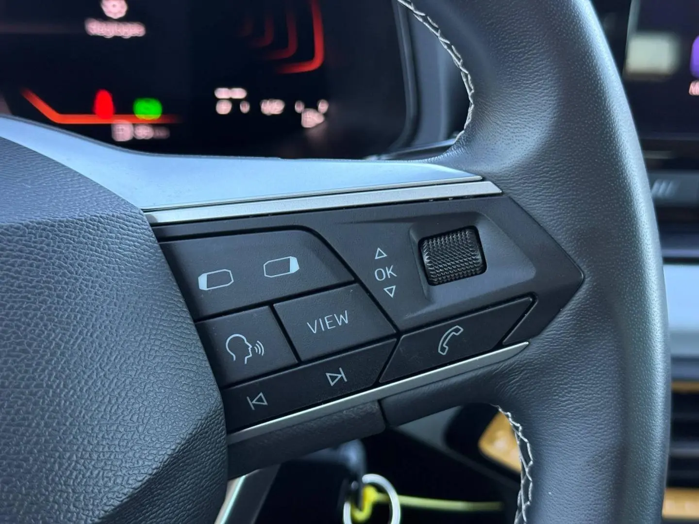 Gros plan sur les commandes multifonctions en cuir du volant côté gauche du SEAT Arona 2025 blanc et noir.