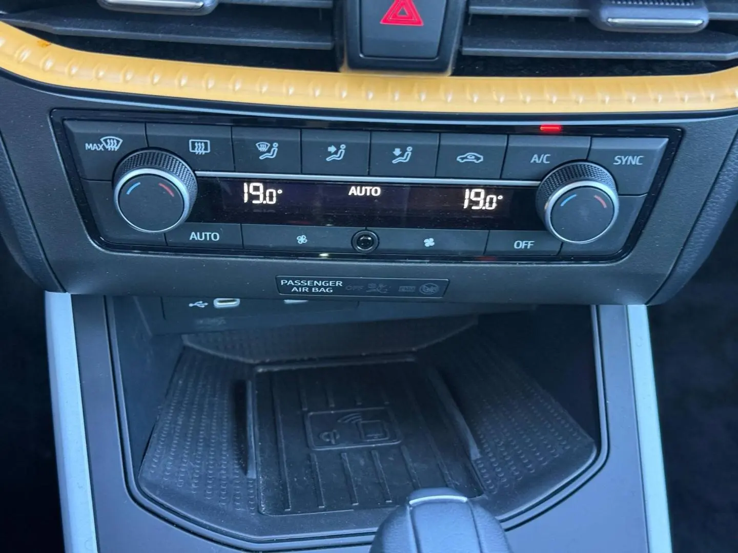 Vue rapprochée de la console centrale du SEAT Arona 2025, montrant la climatisation automatique et un chargeur sans fil noir.