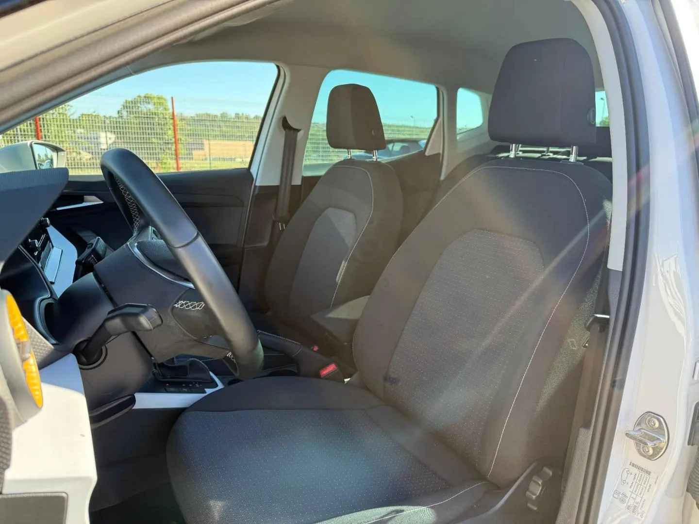 Vue intérieure côté conducteur du SEAT Arona 2025, sièges tissu gris Como et volant cuir multifonction.