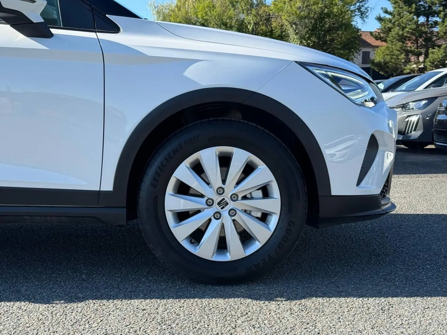 Gros plan sur la roue avant droite d’un SEAT Arona blanc Candy avec jante alu et détails noirs au pare-chocs.