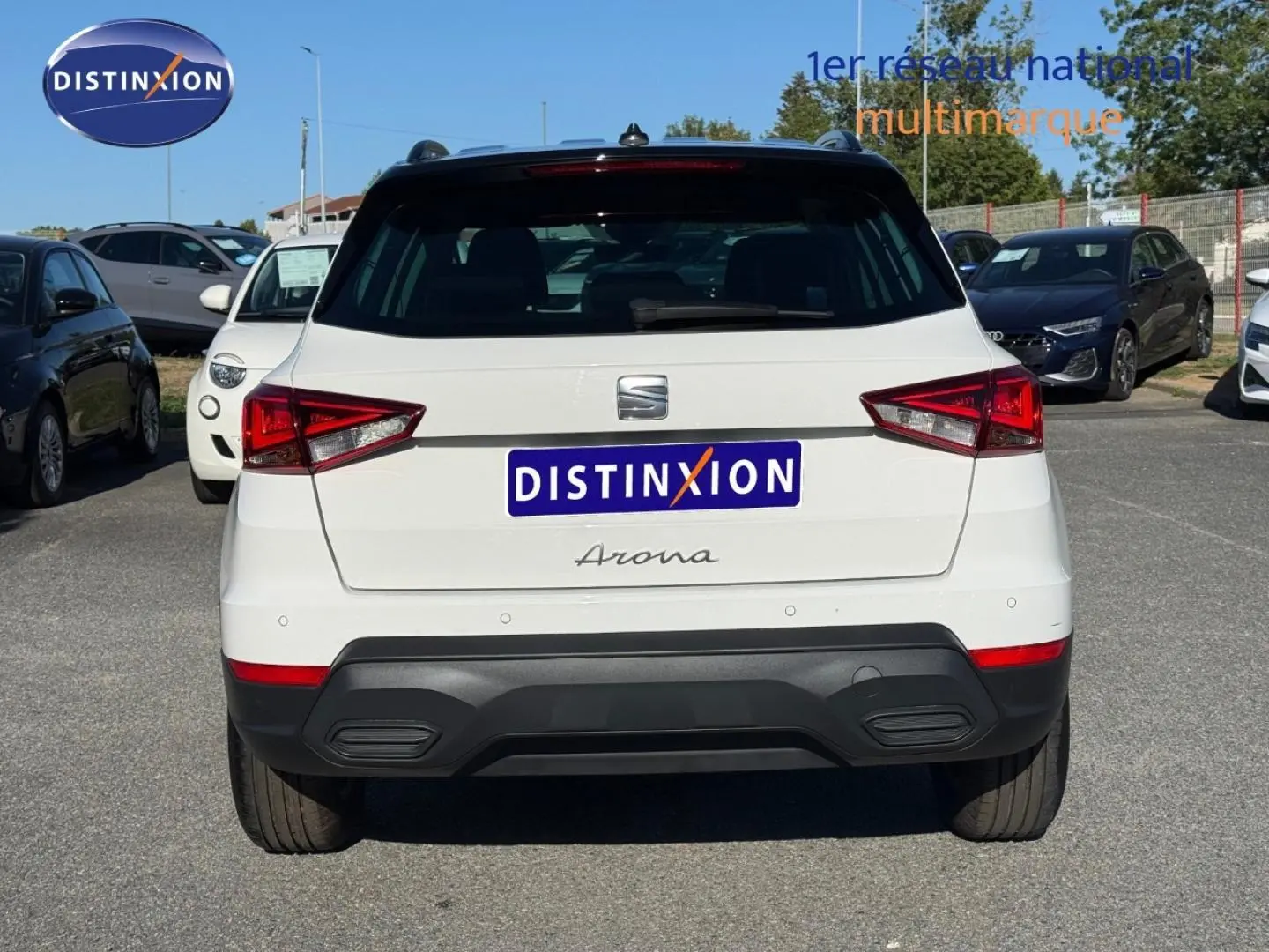 Vue arrière d'un SEAT Arona blanc Candy avec toit noir Minuit, stationné en extérieur sur un parking.