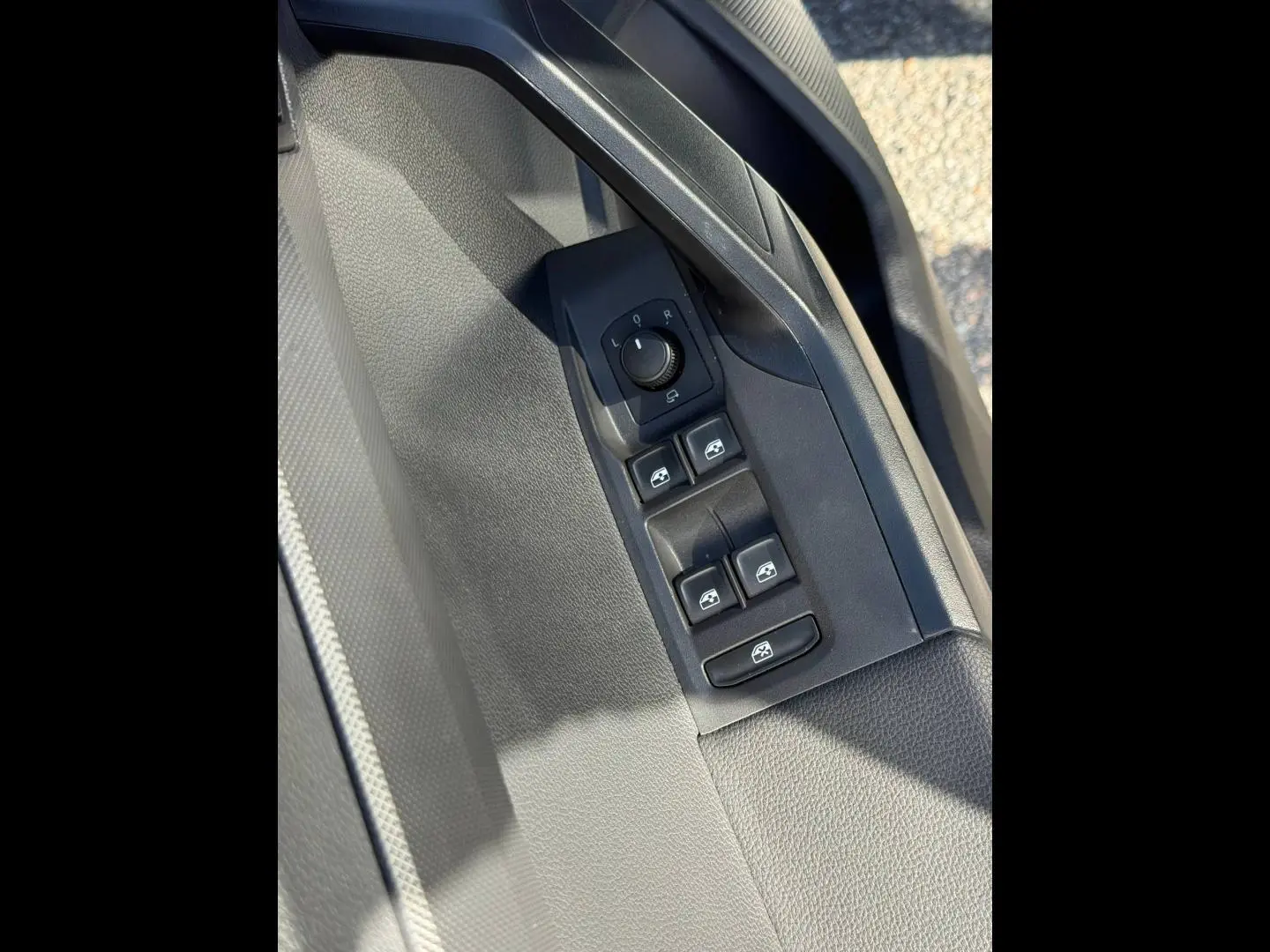 Gros plan sur la commande des vitres et réglage des rétroviseurs côté conducteur, intérieur gris du SEAT Arona 2025.