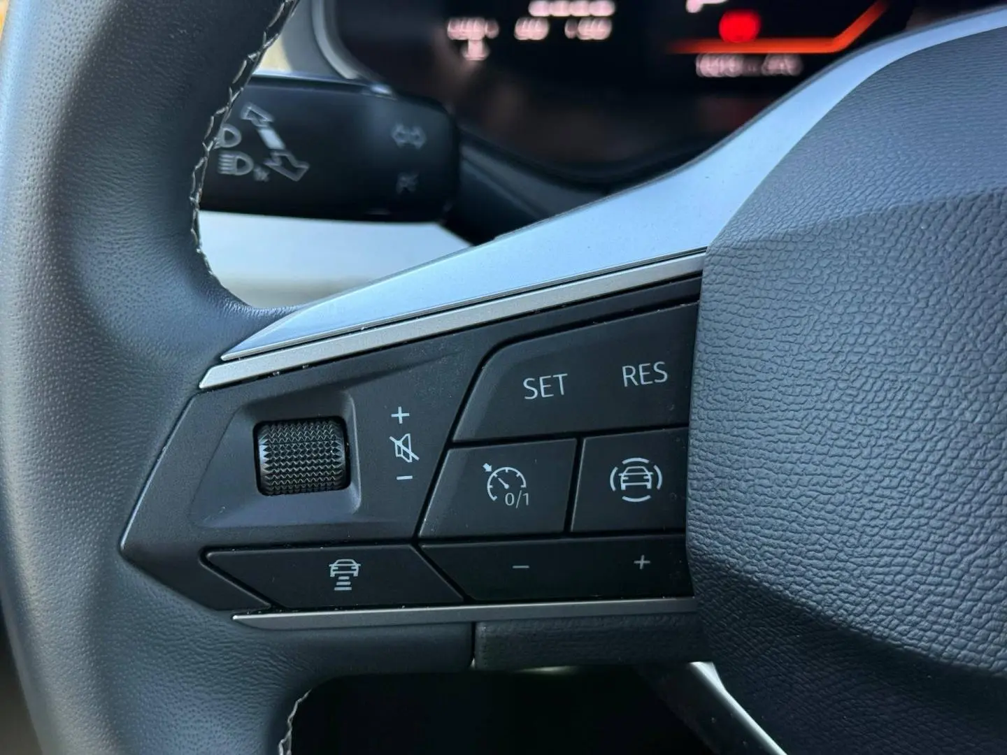 Gros plan sur les commandes de régulateur de vitesse au volant cuir noir du SEAT Arona 2025.
