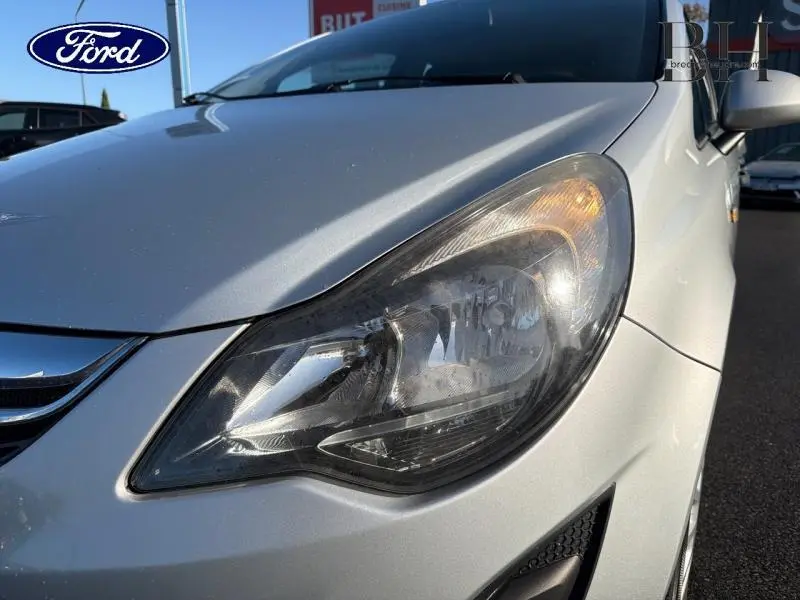 Gros plan sur le phare avant droit d'une Opel Corsa gris minéral, soulignant les détails du bloc optique et la calandre chromée.
