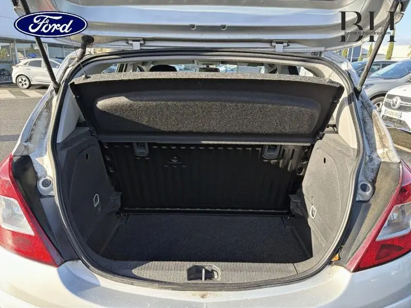 Coffre ouvert vu de l'arrière d'une Opel Corsa gris minéral, montrant l'espace de chargement et la tablette cache-bagages.