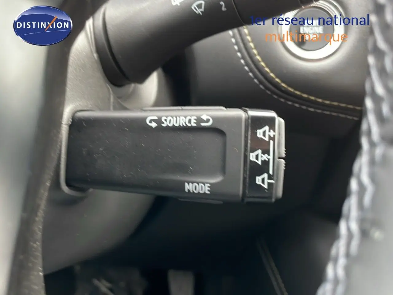 Gros plan sur la commande multimédia au volant d’une Renault Symbioz bleu iron metal, intérieur noir avec coutures contrastées.