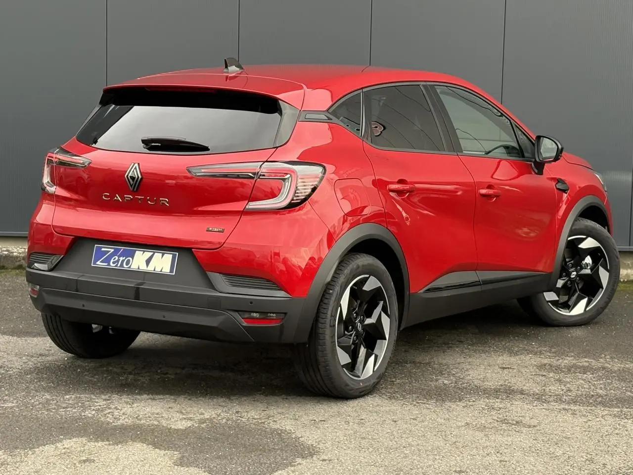 Vue 3/4 arrière droite du Renault Captur Rouge Flamme avec jantes aluminium noires et vitres surteintées.