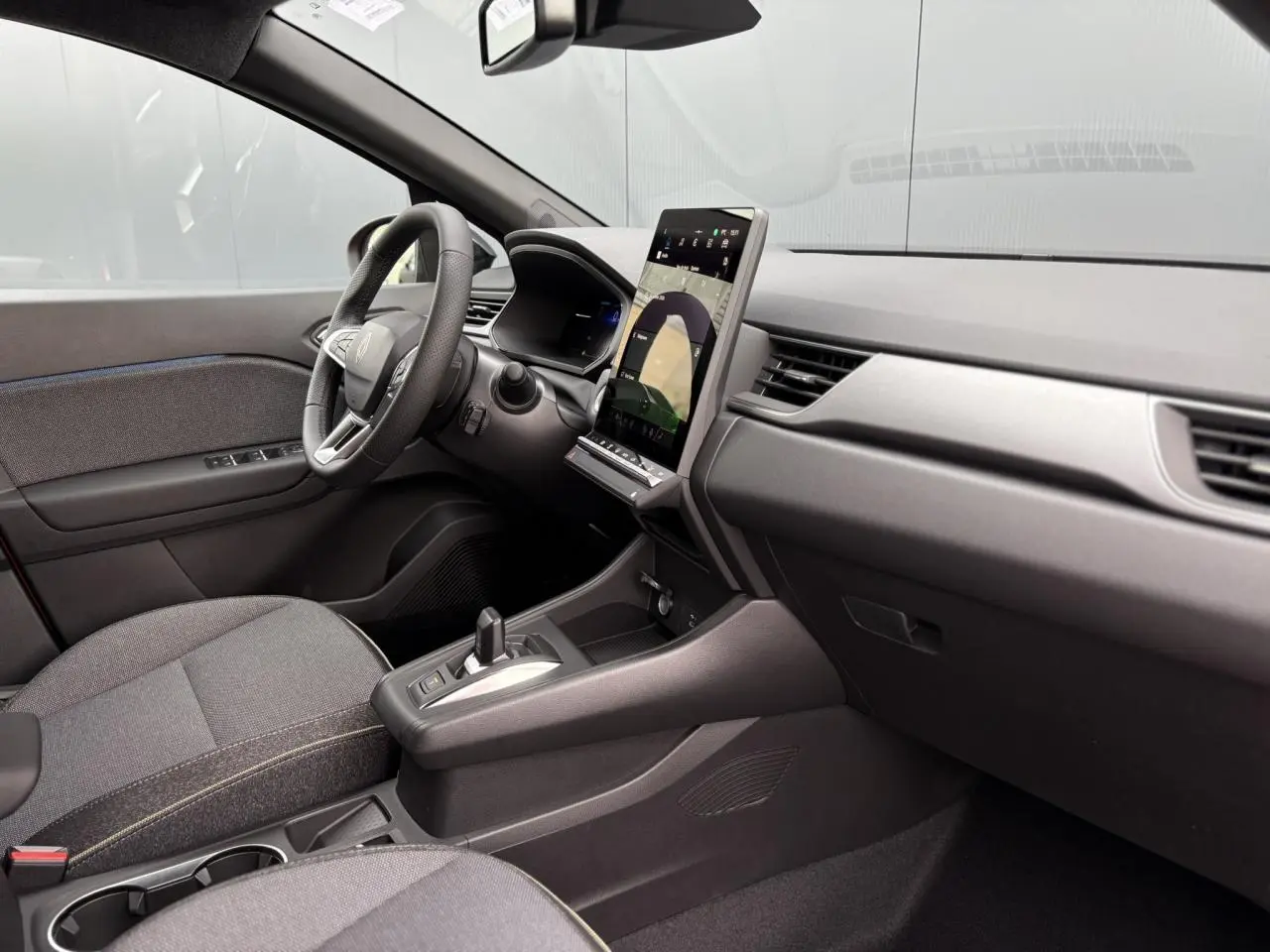 Vue intérieure côté conducteur du Renault Captur 2025 avec tableau de bord moderne et écran tactile vertical.