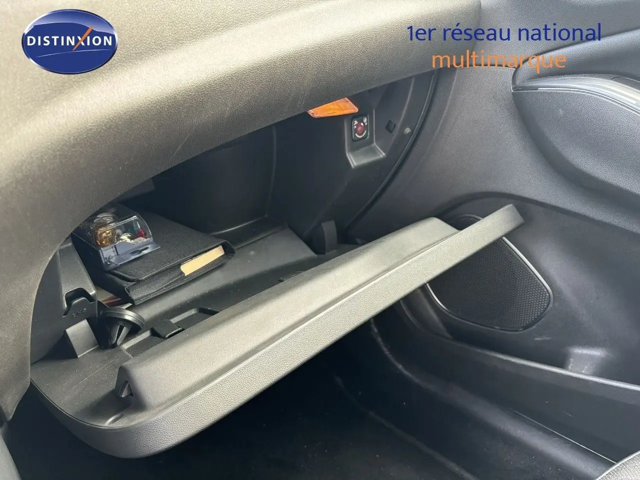 Gros plan sur la boîte à gants ouverte côté passager de l’Opel Grandland X noir, montrant son intérieur et un rangement.