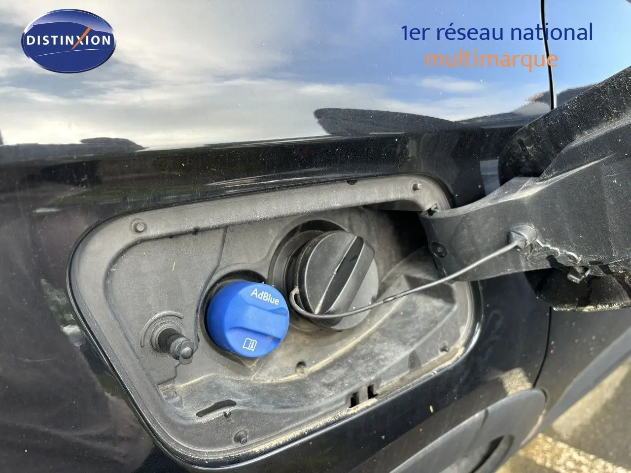 Gros plan sur la trappe à carburant côté gauche d’un Opel Grandland X noir avec bouchon AdBlue visible.