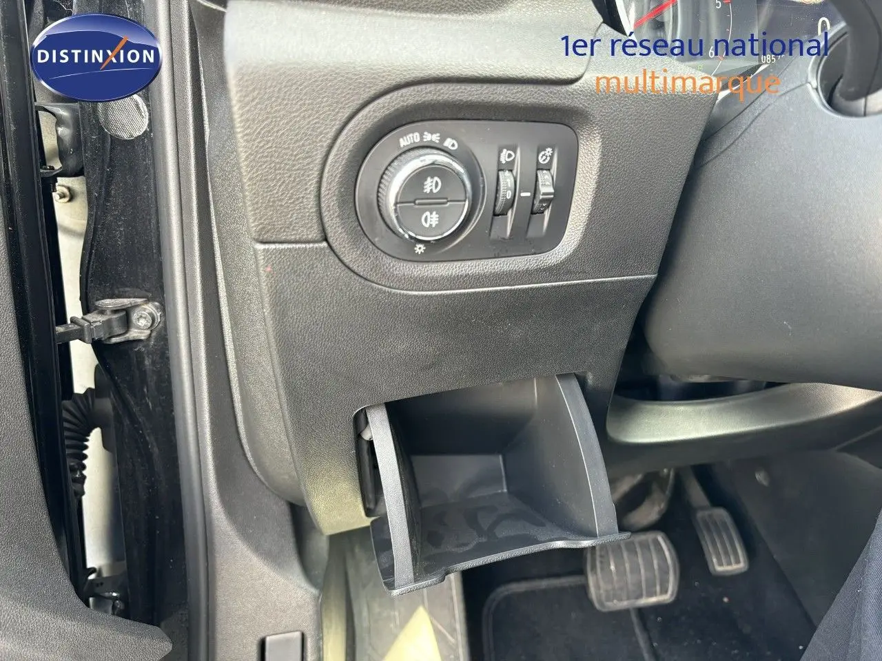 Détail intérieur côté gauche d'un Opel Grandland X noir 2019, montrant les commandes d'éclairage et un petit rangement ouvert.