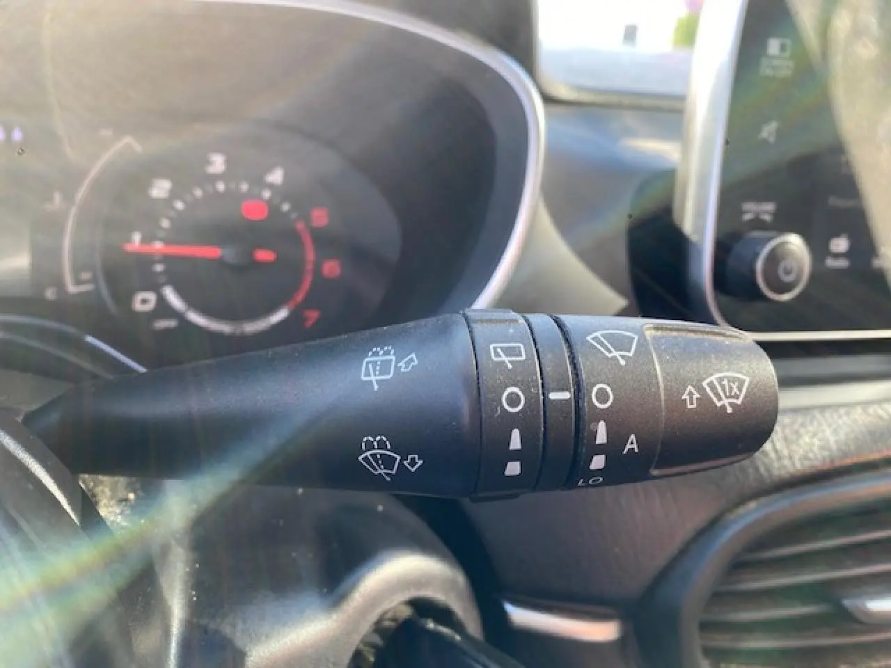 Gros plan sur la commande des essuie-glaces dans l’habitacle du Fiat Tipo bleu, avec tableau de bord flou en arrière-plan.
