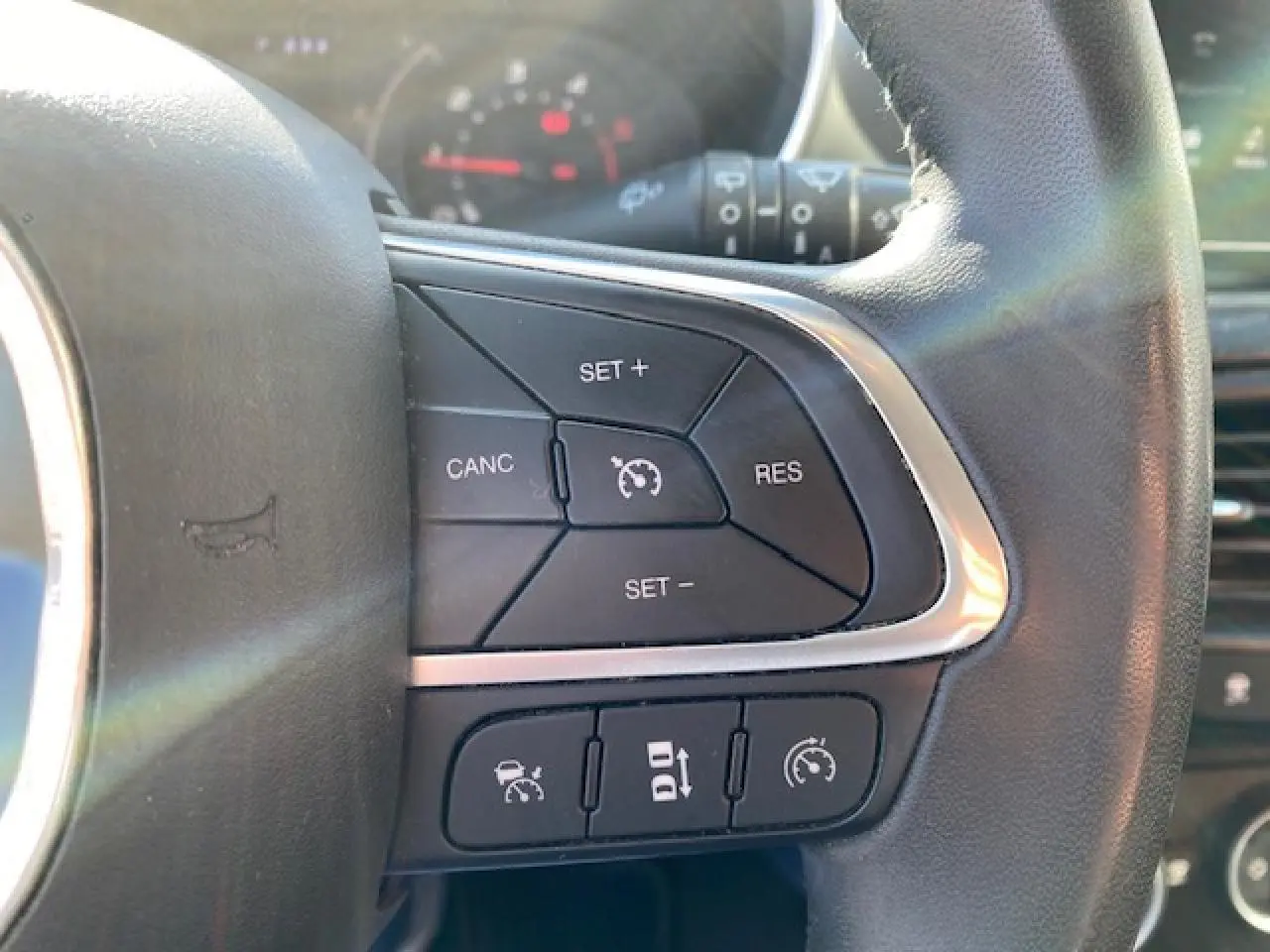 Gros plan sur les commandes de régulateur de vitesse au volant en cuir noir du Fiat Tipo 2018.