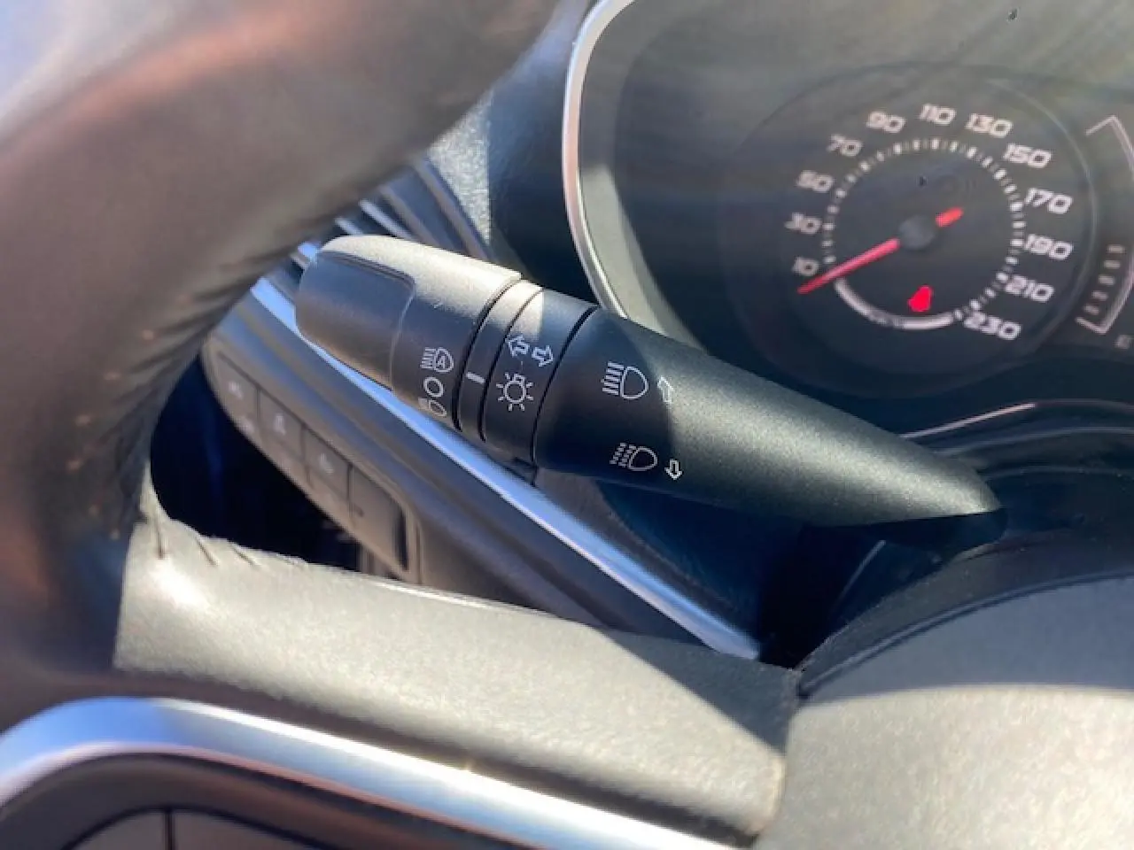 Gros plan sur la manette des feux et clignotants à gauche du volant dans l’habitacle du Fiat Tipo bleu 2018.
