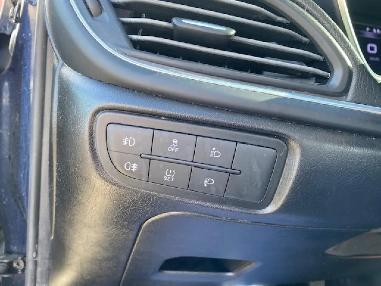 Gros plan sur les commandes d’éclairage et d’aide à la conduite sur la planche de bord noire du Fiat Tipo bleu 2018.