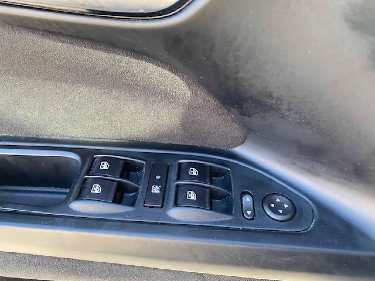 Gros plan sur les commandes des vitres électriques et réglage des rétroviseurs côté conducteur d'une Fiat Tipo bleue.