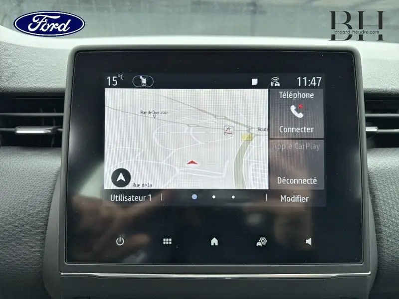 Écran tactile central du tableau de bord d’une Renault Clio blanche, affichant le GPS et les options téléphone.