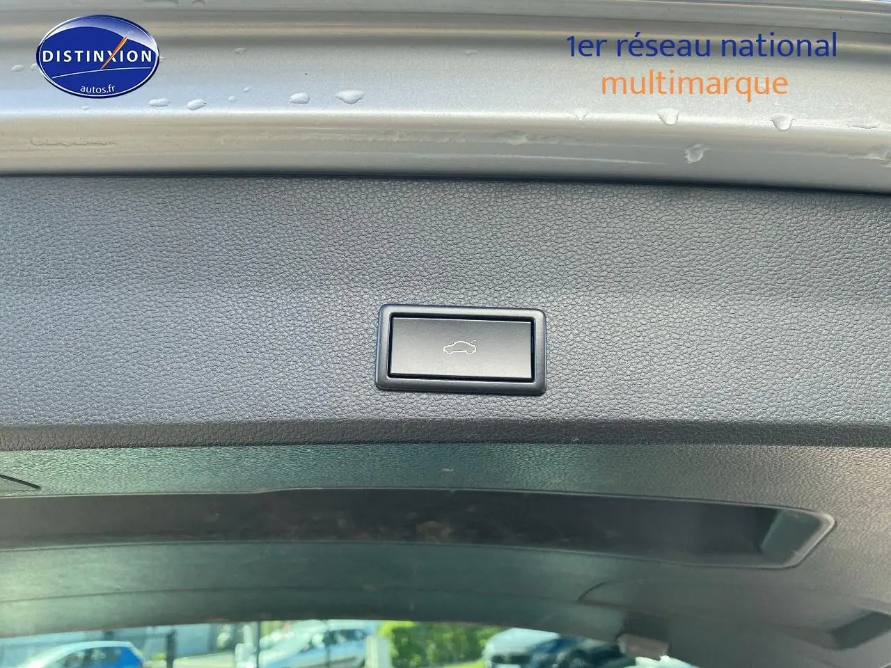 Bouton d'ouverture électrique du hayon sur le bord intérieur du coffre d'un SEAT Ateca gris, vue intérieure arrière.