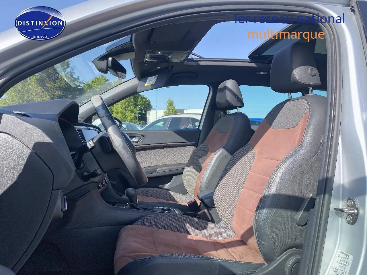 Vue intérieure côté gauche du SEAT Ateca gris 2020, mettant en valeur les sièges sport en alcantara brun et toit panoramique ouvert.