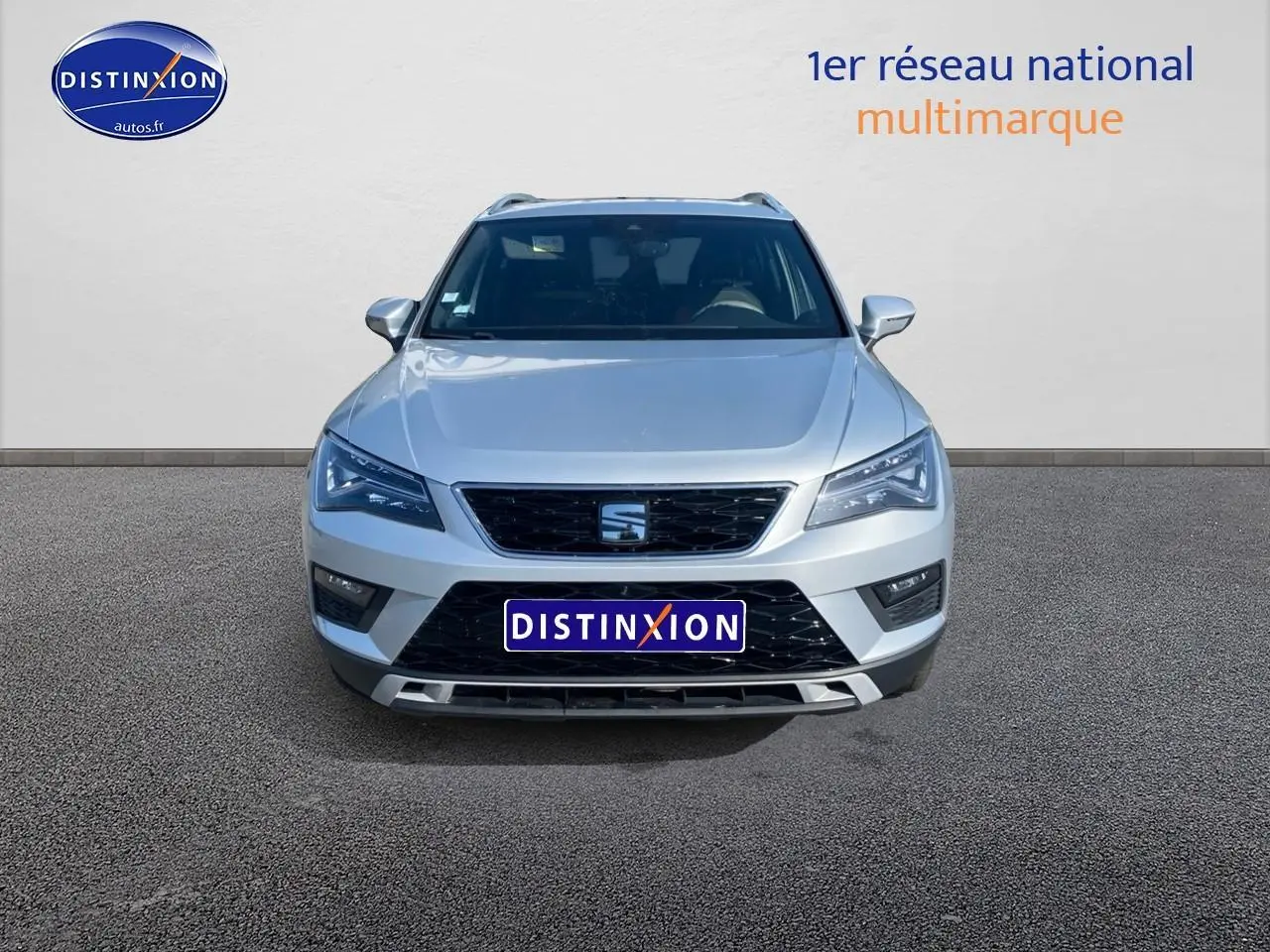 Vue frontale d'un SEAT Ateca gris 2020 avec calandre noire et phares LED distinctifs allumés.