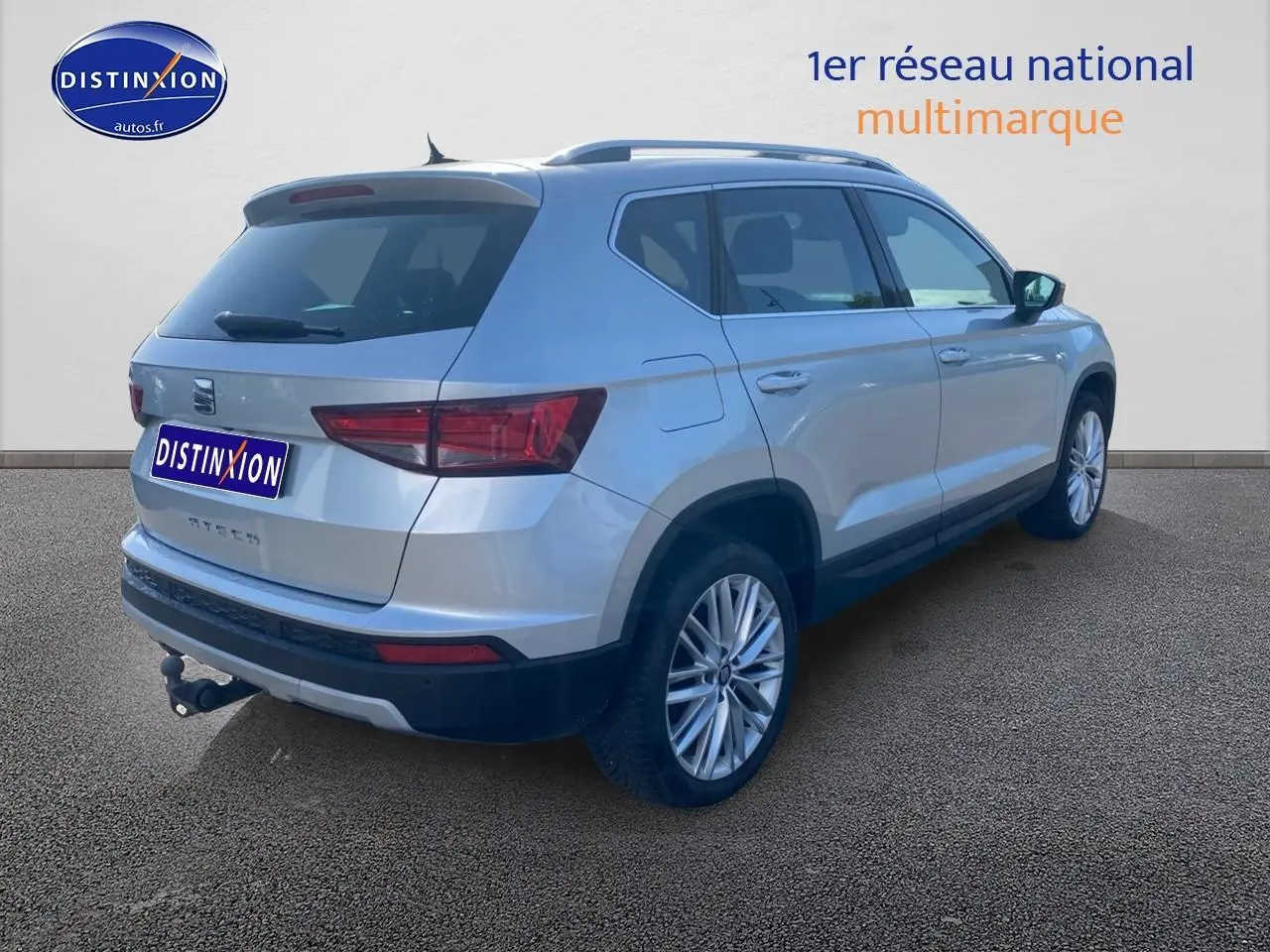Vue 3/4 arrière droite d’un SEAT Ateca gris avec jantes alu et attelage visible sur fond neutre.