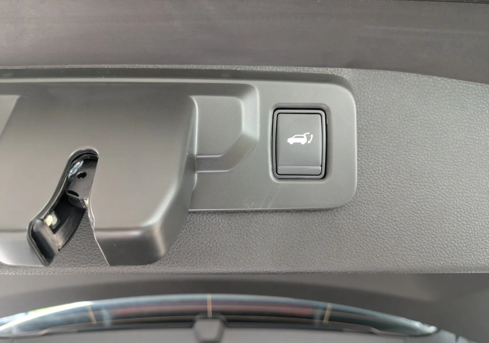Gros plan sur le bouton d'ouverture électrique du coffre dans l'intérieur gris du Renault Symbioz 2026.