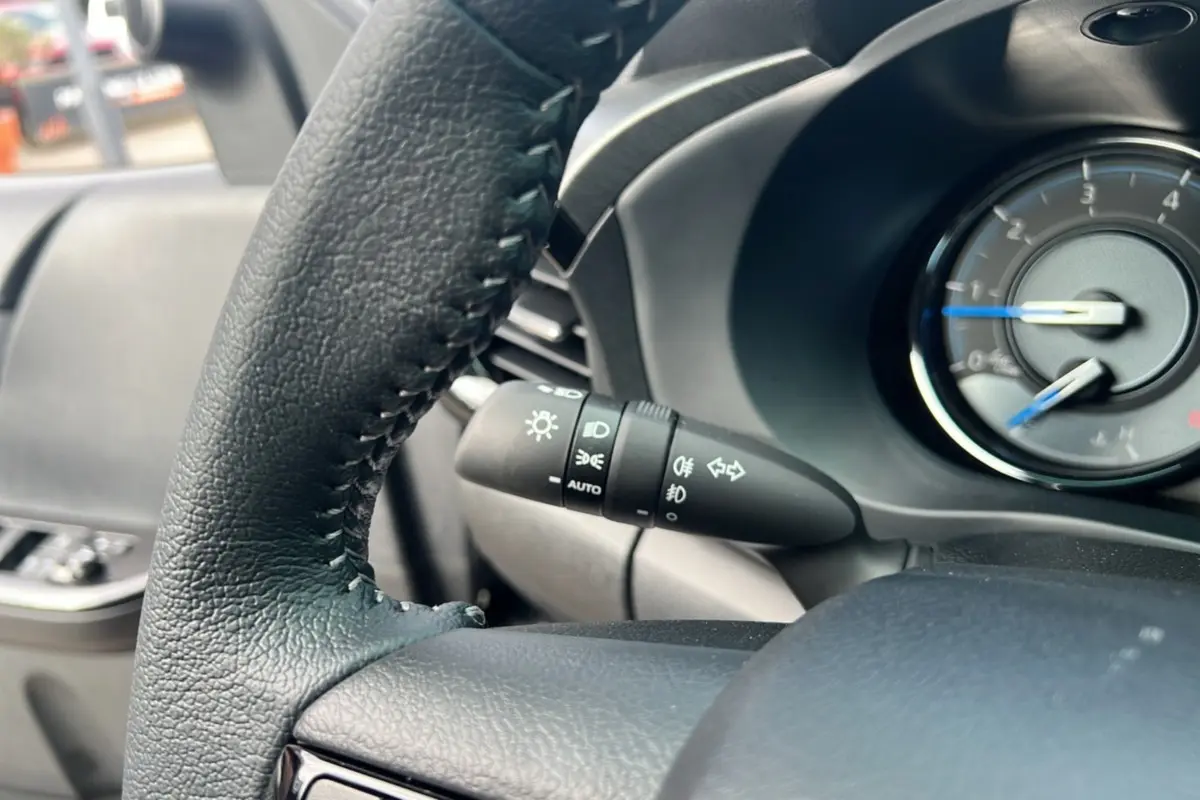 Gros plan sur le volant et la commande des phares du Toyota Hilux 4x4 gris atlas, tableau de bord partiellement visible.