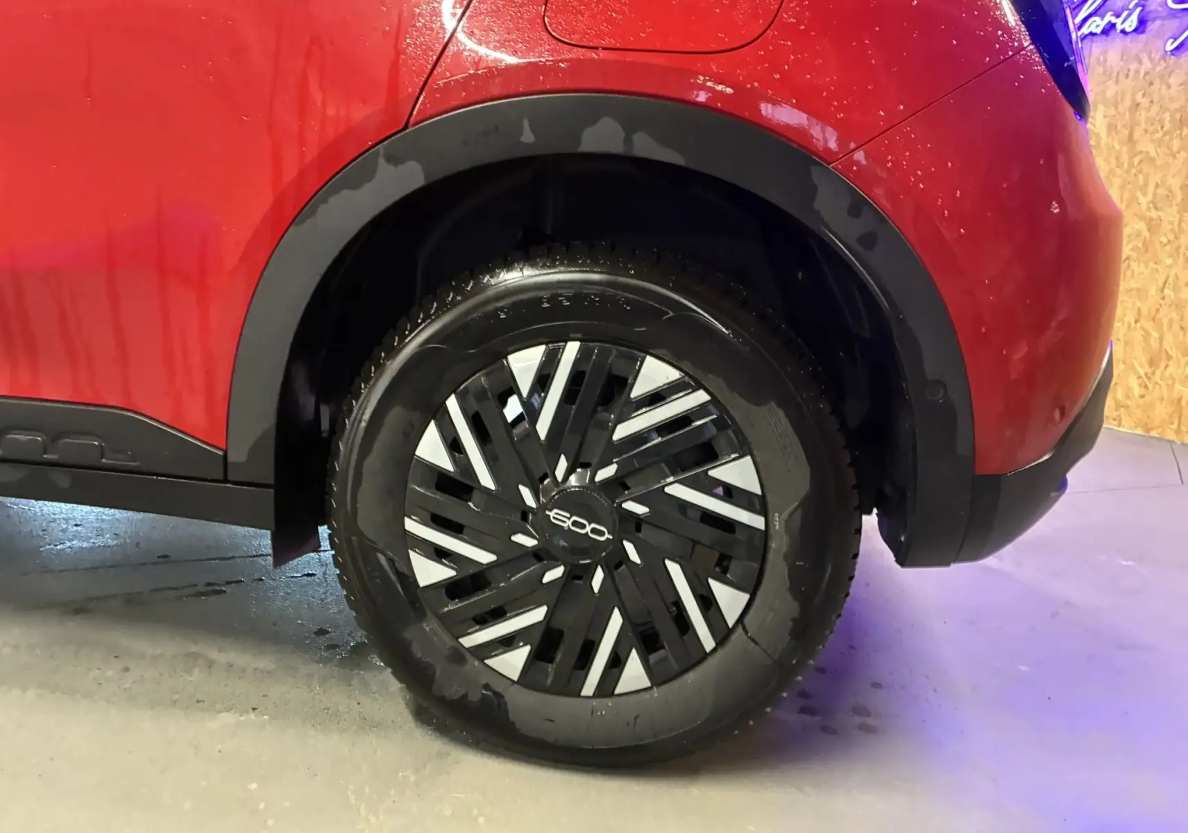 Gros plan sur la roue arrière droite d'une FIAT 600 rouge 2024, avec jante noire et argentée au design géométrique.