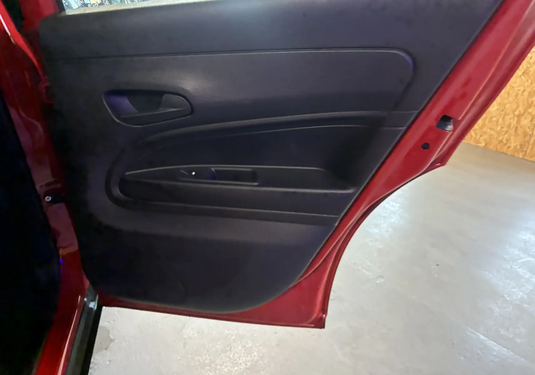 Vue rapprochée de la porte arrière gauche rouge du FIAT 600 1.2 HYBRID 100, intérieur noir avec poignée intégrée.