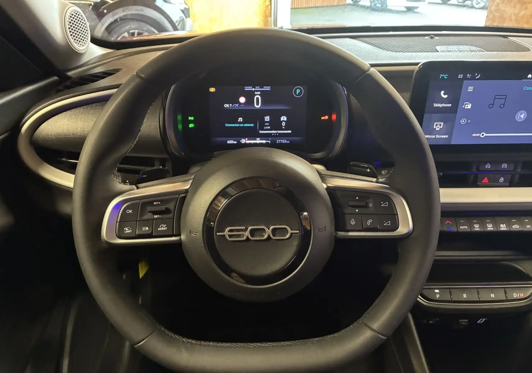 Vue intérieure centrée sur le volant noir du Fiat 600 1.2 Hybrid 2024 avec tableau de bord numérique et écran tactile.