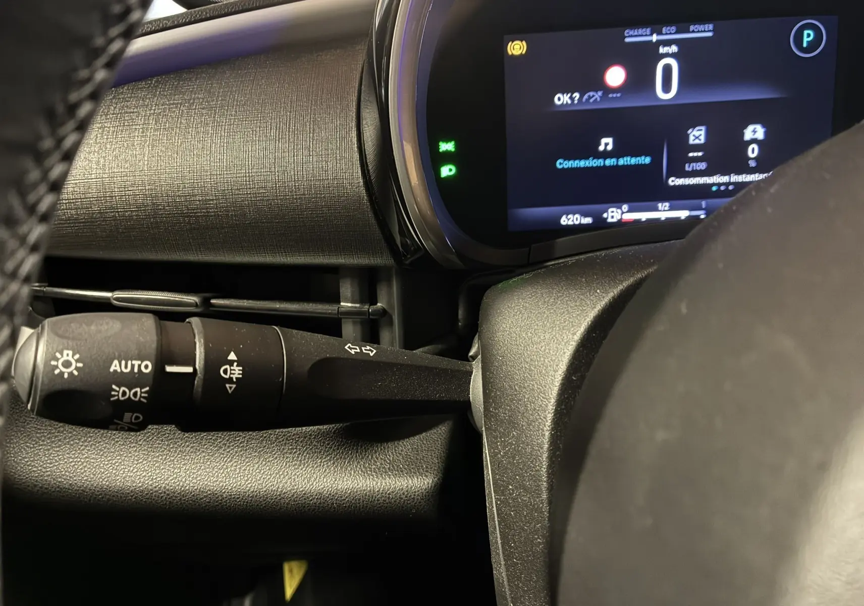 Détail du combiné d'instruments et du commodo d'éclairage à gauche du volant dans la FIAT 600 rouge 2024 hybride.