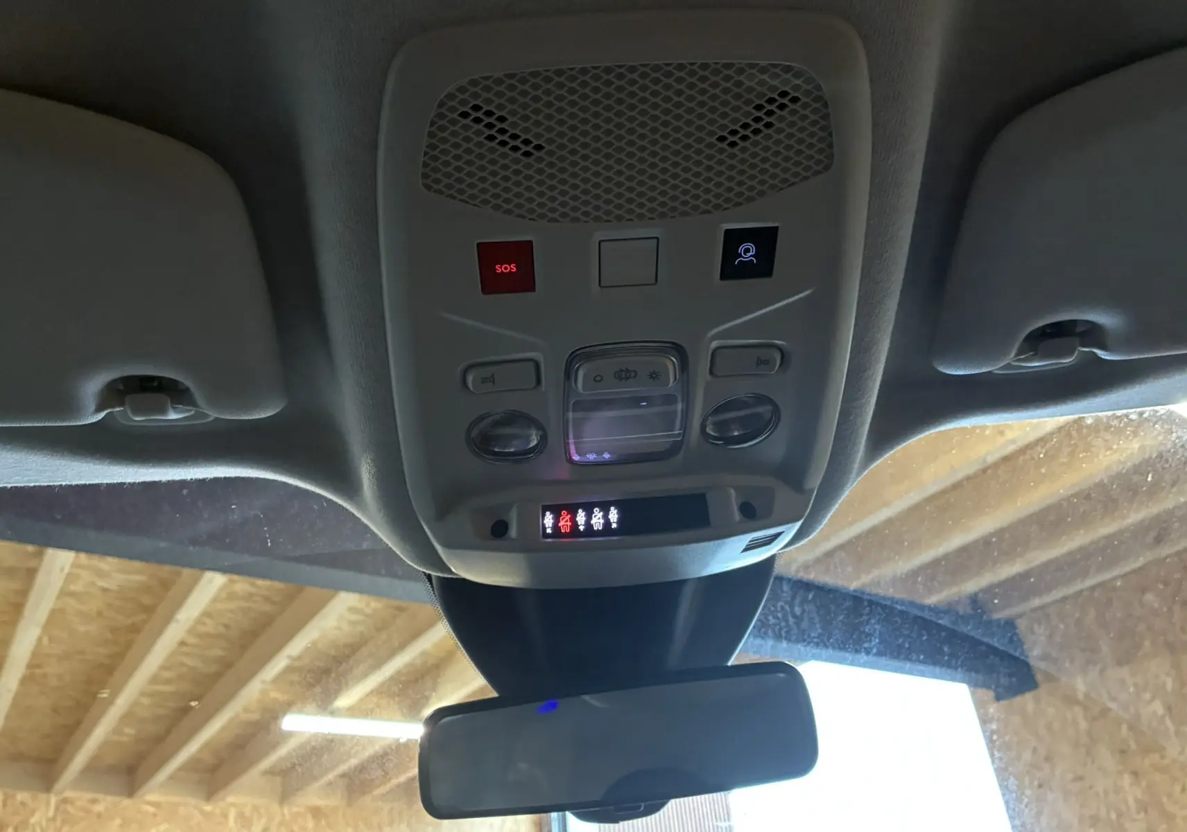 Vue intérieure en contre-plongée du plafonnier avec commandes d'éclairage et boutons SOS dans une Fiat 600 rouge 2024.