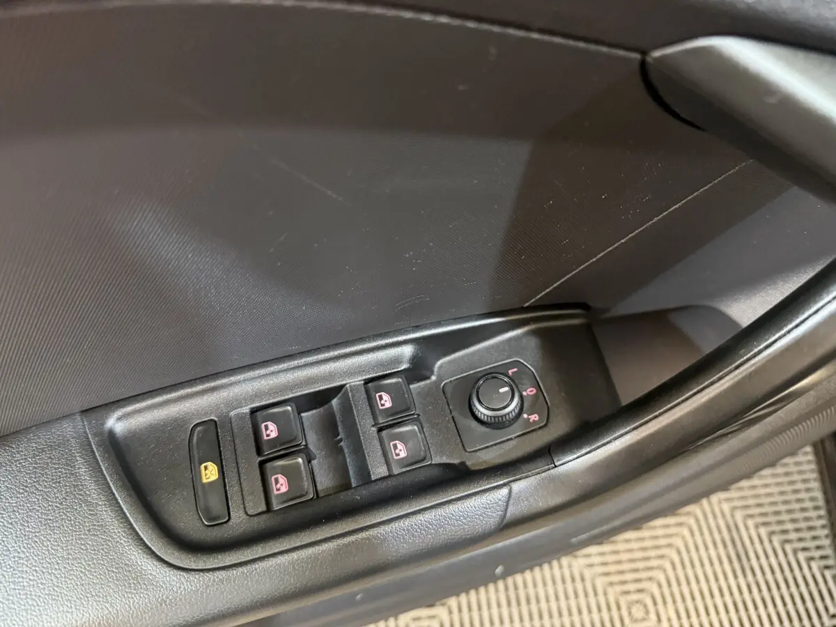 Gros plan sur les commandes des vitres et des rétroviseurs côté conducteur d’une Audi A1 noire de 2021.