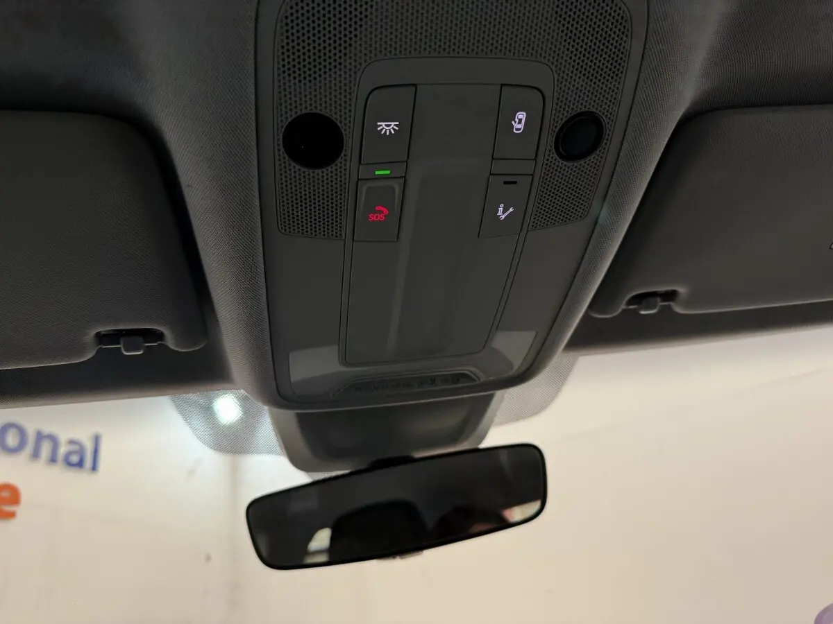 Vue intérieure du plafonnier avec boutons SOS et éclairage, miroir intérieur et pare-soleil gris d'une Audi A1 noire.