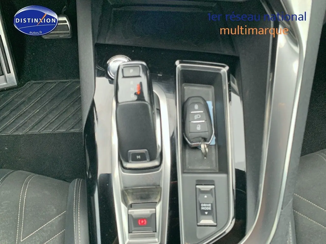 Vue rapprochée de la console centrale noire brillante du Peugeot 3008 gris platinium avec levier de vitesse et clé.