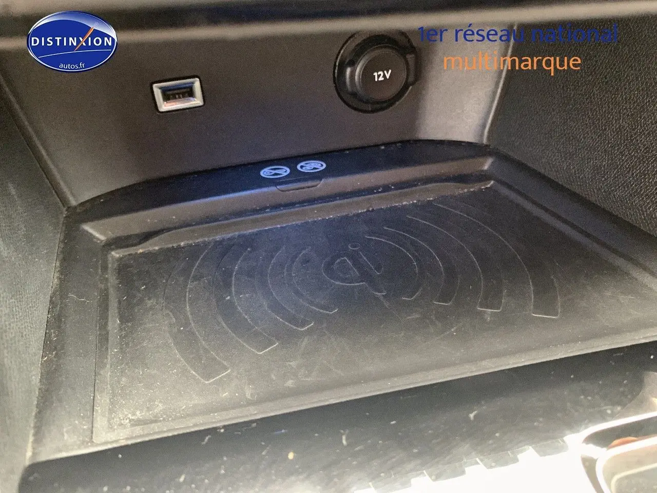 Gros plan sur la zone de recharge sans fil Qi et prise 12V dans l'habitacle du Peugeot 3008 gris platinium.