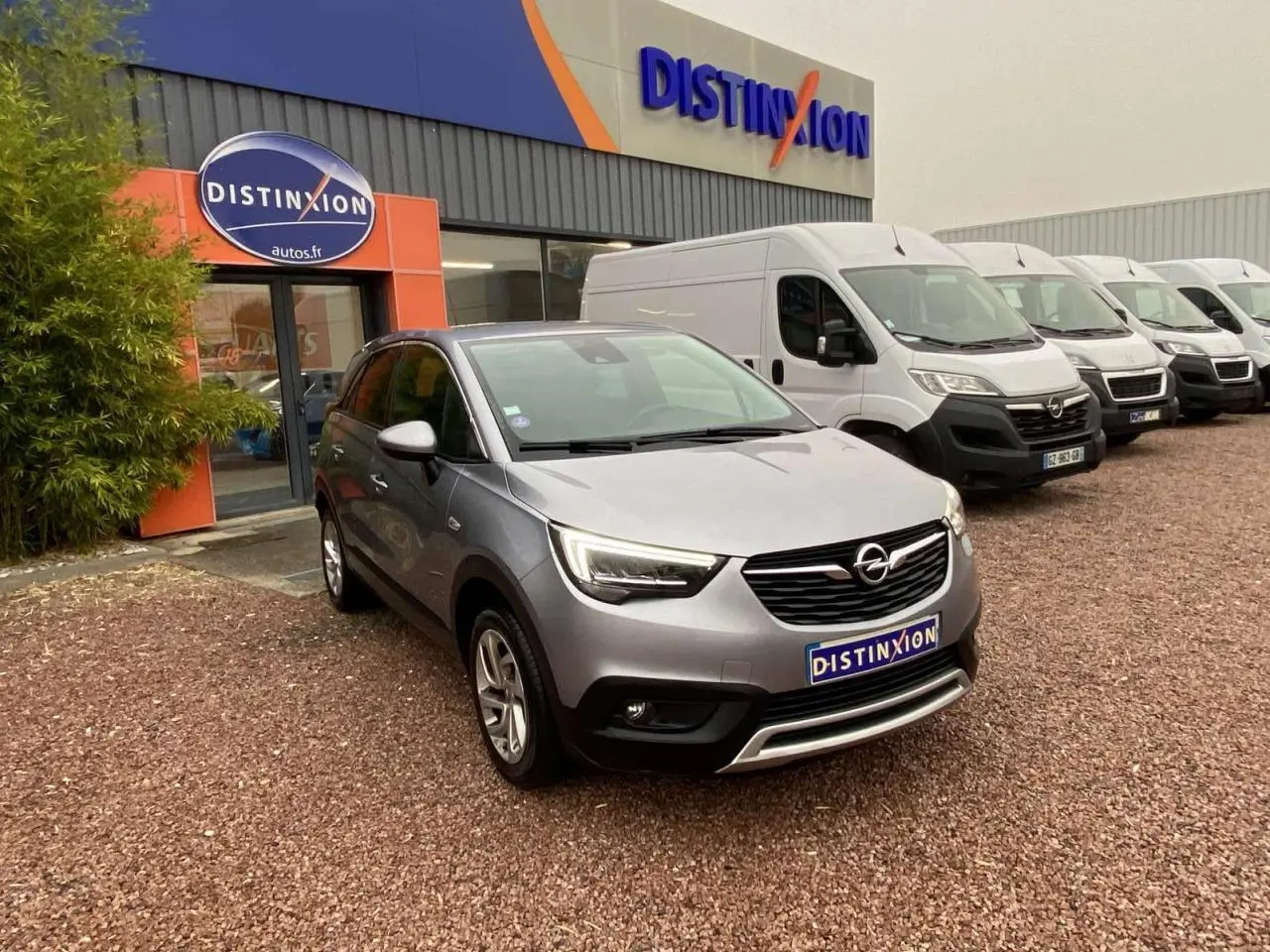 Opel Crossland X gris métallisé en 3/4 avant droit, stationné devant un concessionnaire Distinxion.